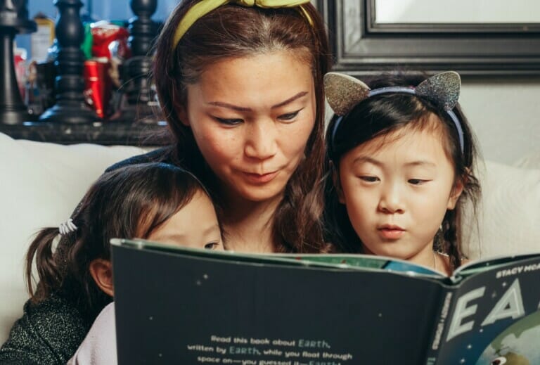 A Woman and Her Children Reading a Book About the Earth